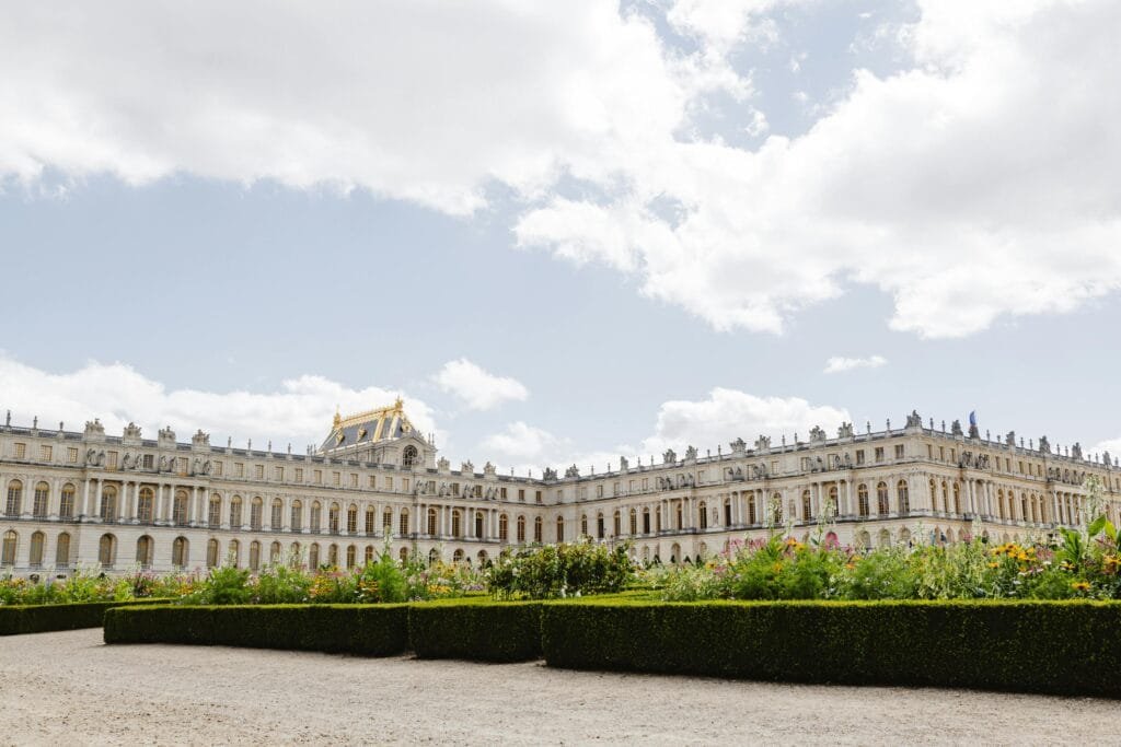 Stunning view of the Palace of Versailles with lush gardens under a bright sky.
